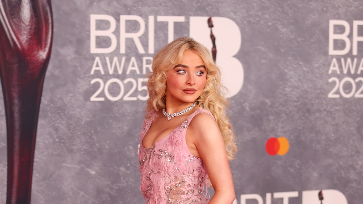 Sabrina Carpenter en la alfombra roja de los BRIT Awards 2025, luciendo un vestido rosa con detalles brillantes.