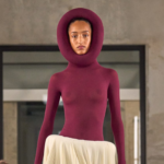 Modelo en la pasarela del desfile de Alaïa en París Fashion Week 2025, luciendo un diseño de silueta escultórica con detalles vanguardistas. La colección fusiona estructuras innovadoras con la esencia atemporal de la casa de moda.