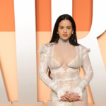 Rosalía en la fiesta de Vanity Fair post-Oscars 2025, luciendo un vestido blanco de transparencias con mangas largas y detalles románticos.