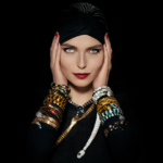 Retrato de modelo con mirada intensa, usando múltiples brazaletes de la colección Serpenti de Bulgari y un turbante negro.