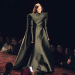 Desfile de Balenciaga en la Semana de la Moda de París 2025, con una modelo luciendo un vestido de líneas vanguardistas y una estética futurista en un ambiente oscuro e impactante.