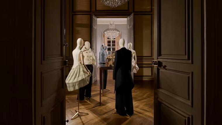 Presentación de la colección de Loewe en la Semana de la Moda de París 2025, donde maniquíes en una lujosa sala exhiben prendas estructuradas con juegos de volúmenes y tejidos innovadores.