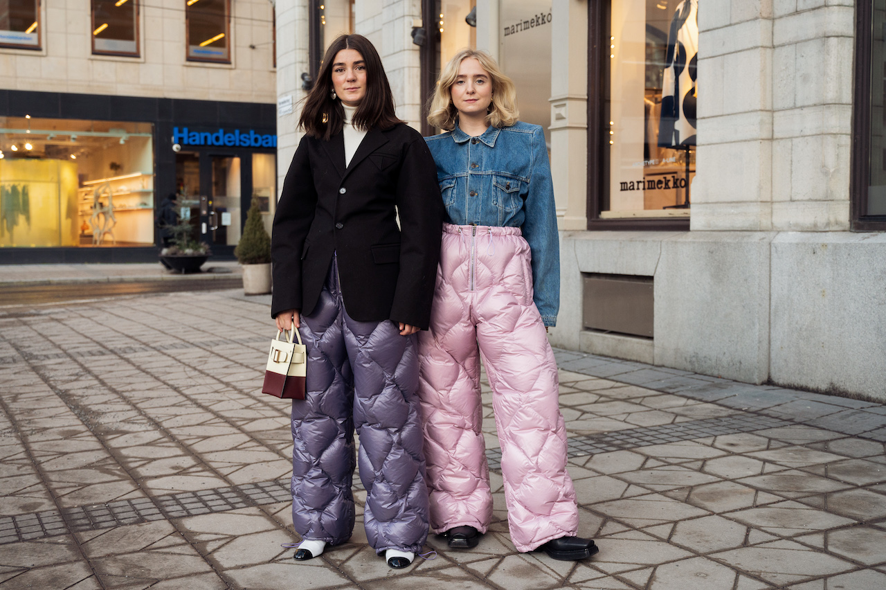 Linn Eklund y Fanny Ekstrand con pantalones acolchados de nylon en tonos morado y rosa de Miu Miu, captadas fuera del desfile de Beckmans College of Design durante la Semana de la Moda de Estocolmo.